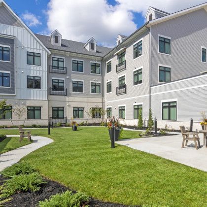 Exterior of a gray multi-story building with a manicured lawn and patio.