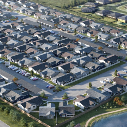 Aerial view of a suburban neighborhood with rows of houses, cars, and streets near a body of water.