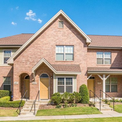 Brick townhomes with tan doors and windows against a blue sky.