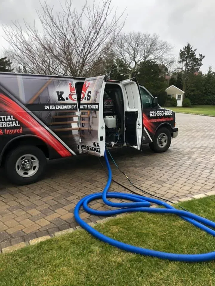 A van with the door open and a blue hose attached to it.