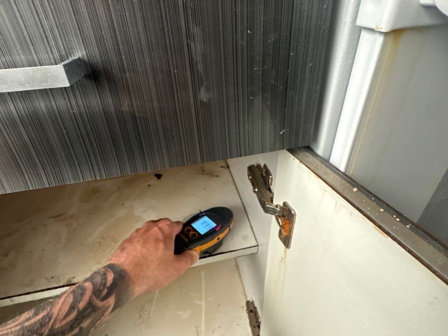 Taking moisture readings of kitchen cabinets after flood at home in Westhampton Beach NY