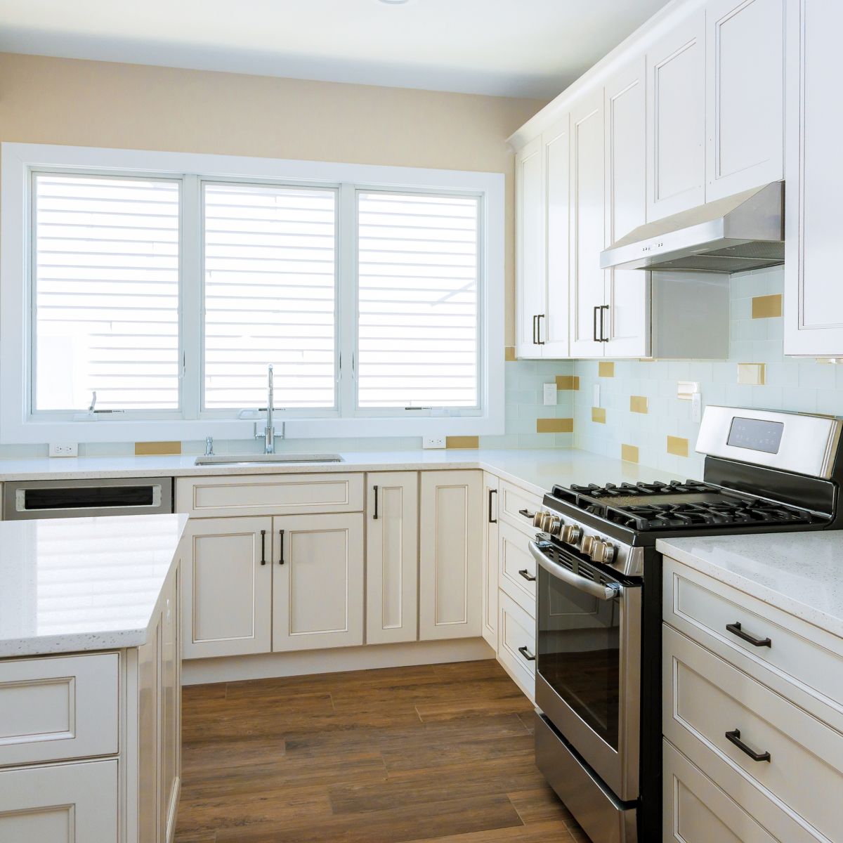 Bright white kitchen with wood floor, white cabinets, stainless stove, and window shutters
