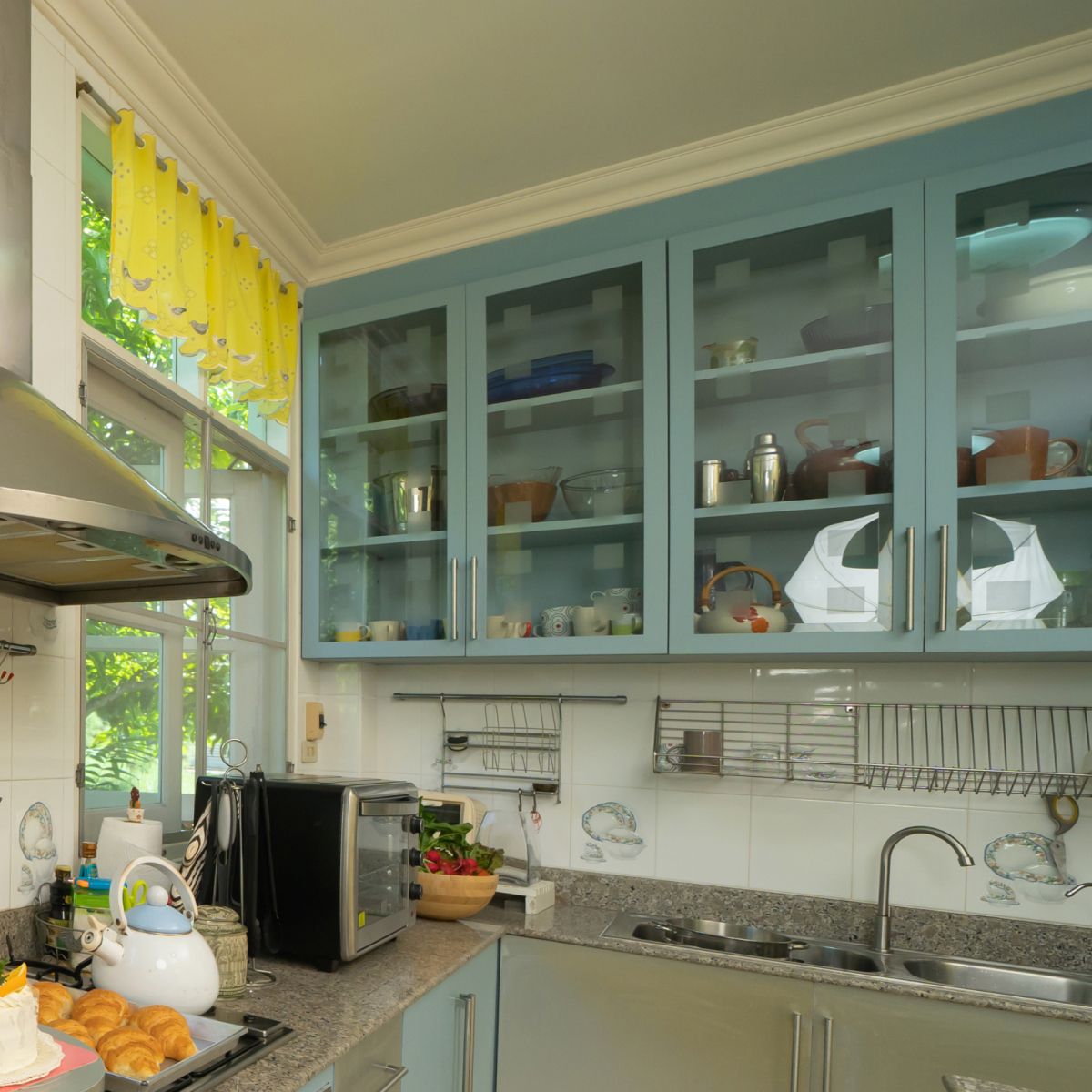 Bright kitchen with blue cabinets, granite counters, sink, and a yellow window blind