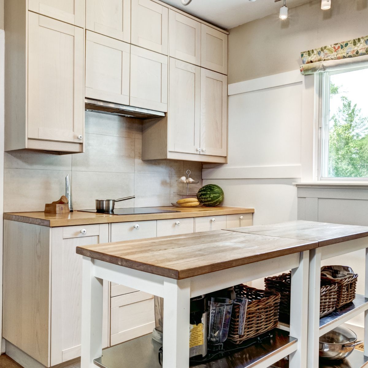 Bright white kitchen with wooden countertops and a central island with baskets underneath