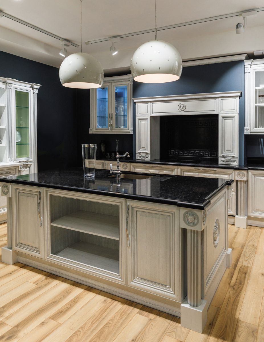 Modern kitchen island with black countertop, cream cabinetry, and pendant lights beneath a white ceiling