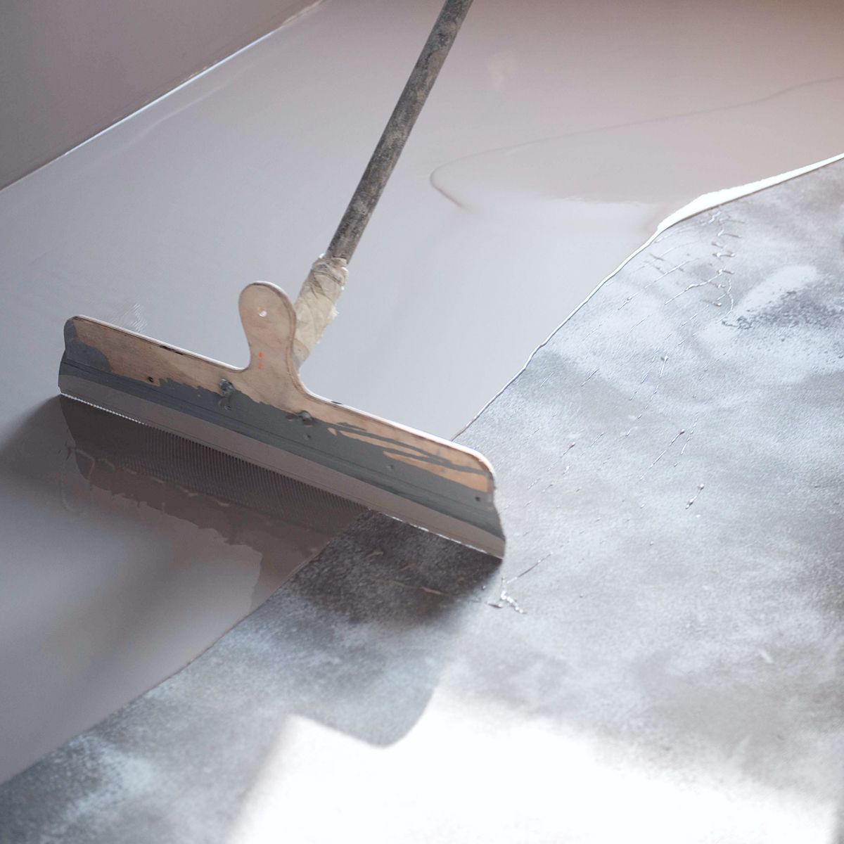 Squeegee scraping water off a white surface, leaving a clean dry area