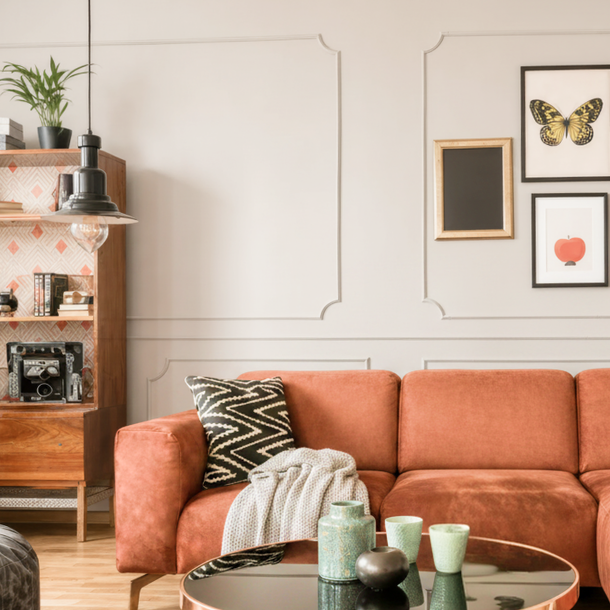 Orange sofa beneath framed butterfly and abstract wall art in a bright living room