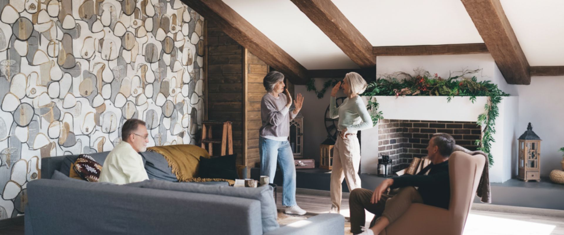 People relaxing in a rustic living room with stone wall, exposed beams, and a lit fireplace