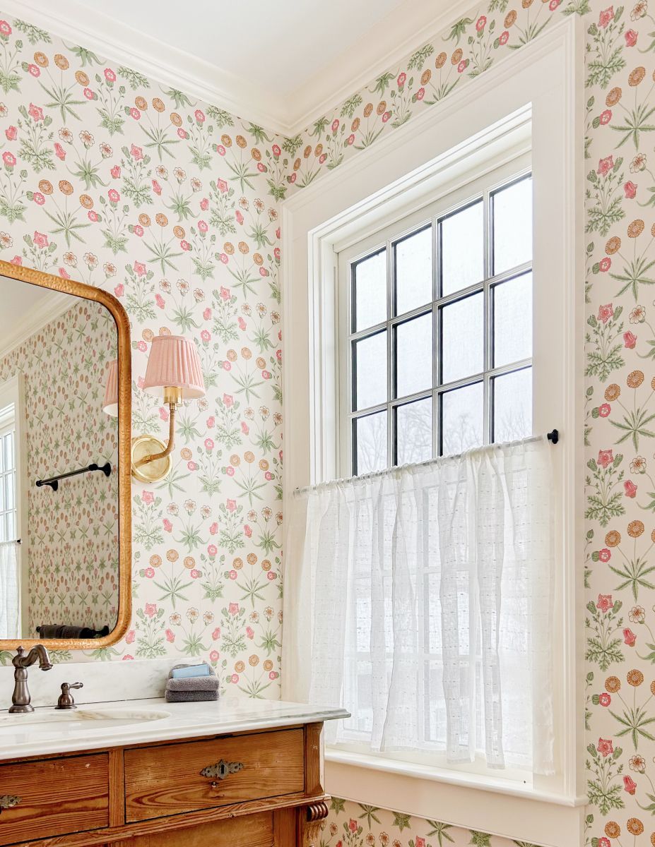 Bright bathroom with floral wallpaper, window light, mirror, and wooden vanity sink
