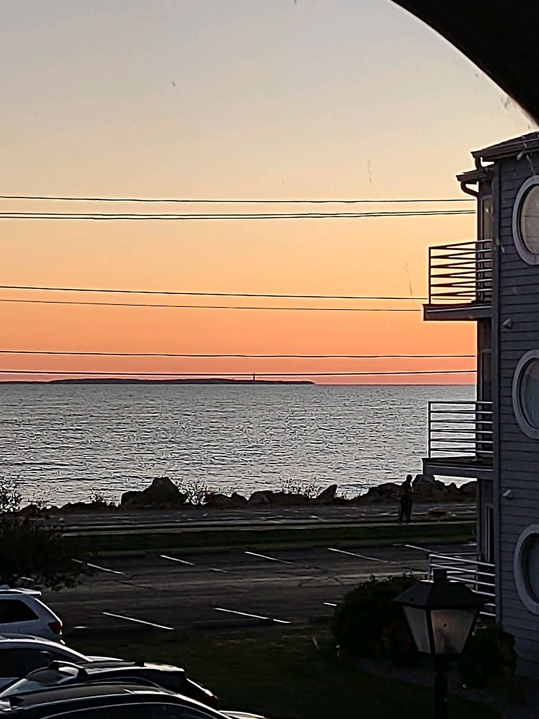 A sunset over the ocean with a building in the foreground