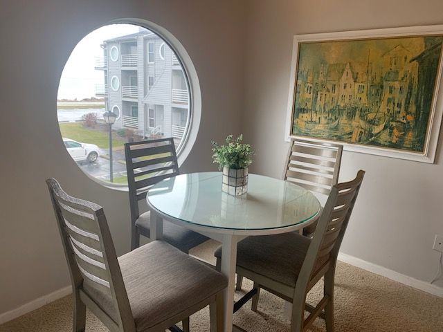 A dining room with a round table and chairs and a painting on the wall.