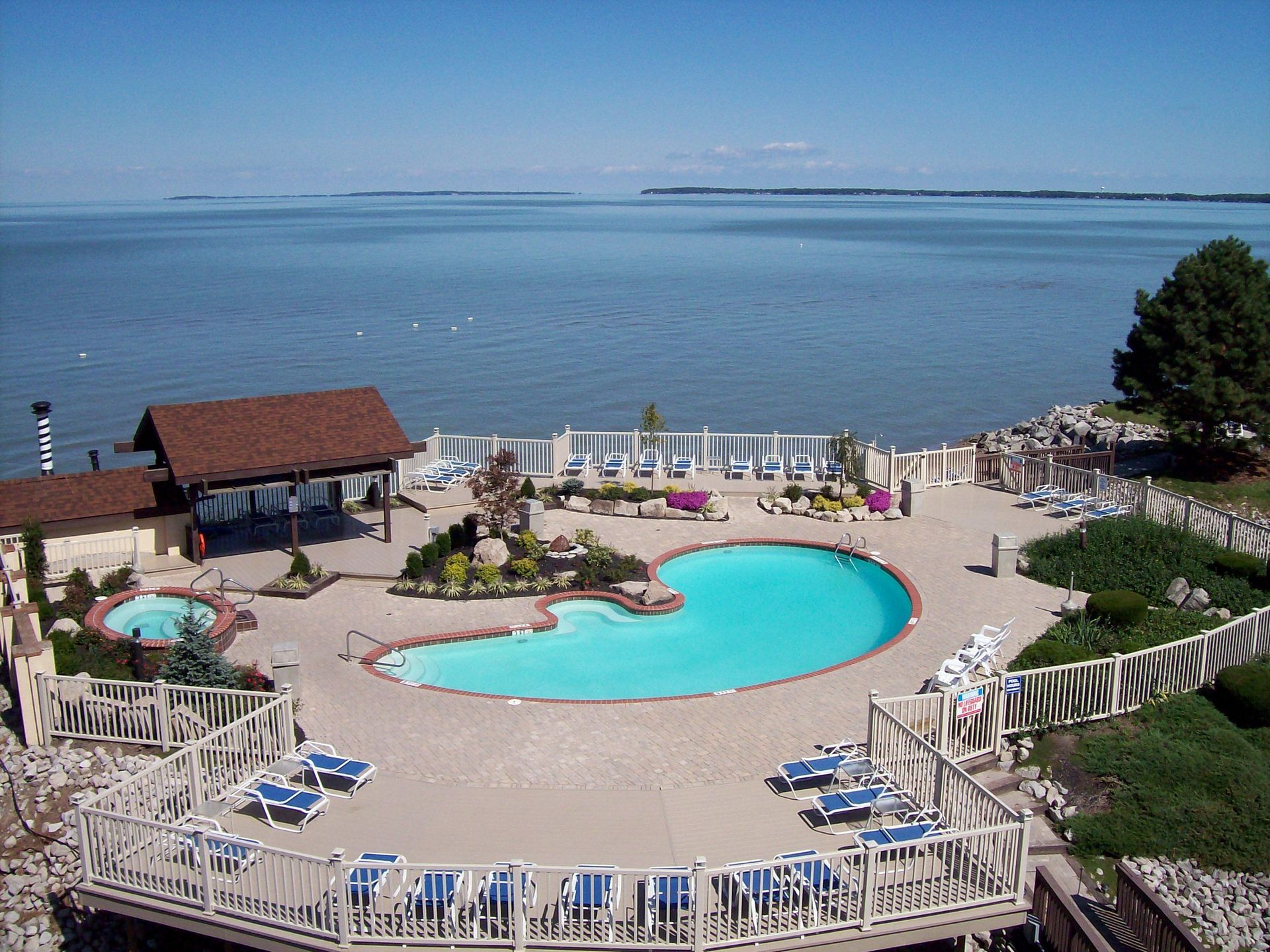 A large swimming pool surrounded by chairs and umbrellas overlooking the ocean