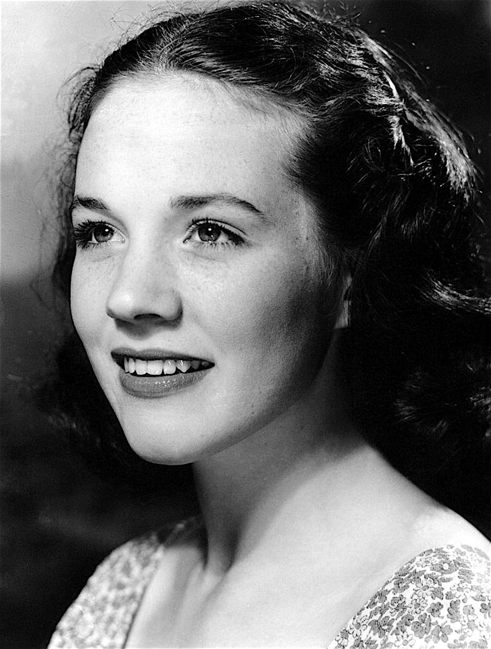 A black and white photo of a young woman smiling.