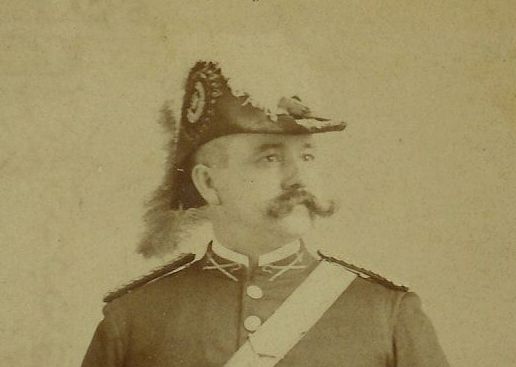 A man with a mustache is wearing a feathered hat.