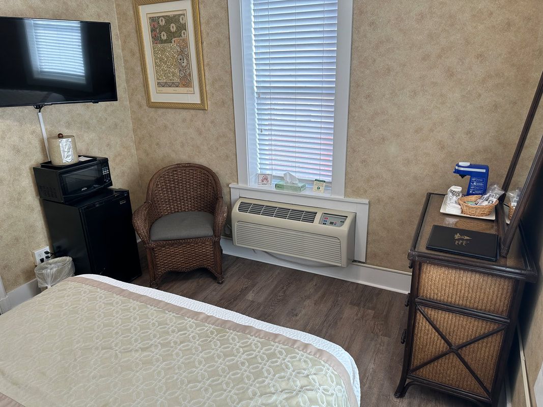 A hotel room with a bed , chair , dresser and television.