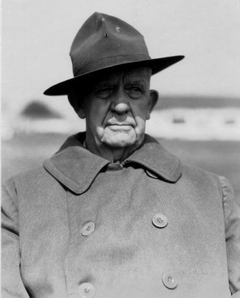 A black and white photo of a man wearing a hat and coat