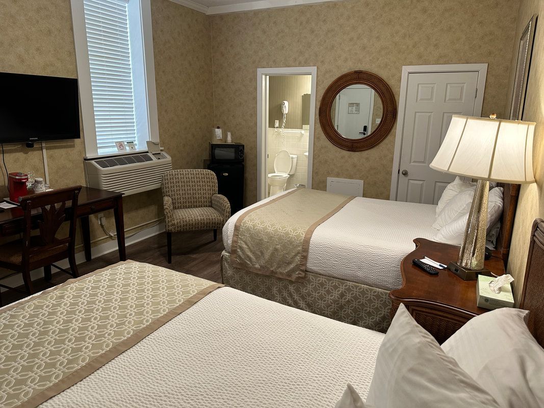 A hotel room with two beds , a desk and a television.