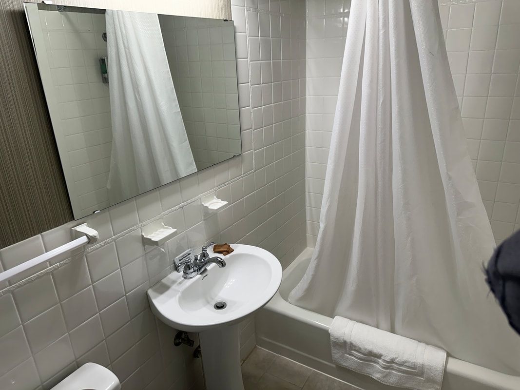 A bathroom with a sink , toilet , shower and mirror.