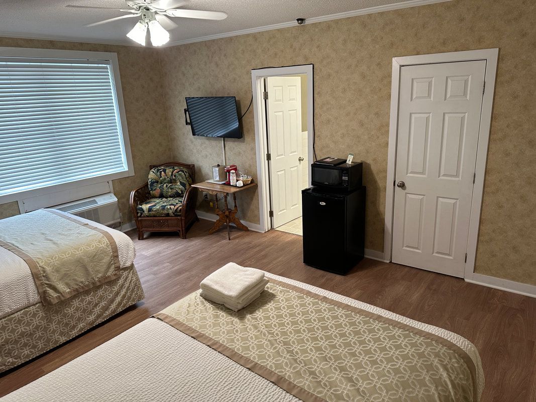 A hotel room with two beds , a chair and a television.