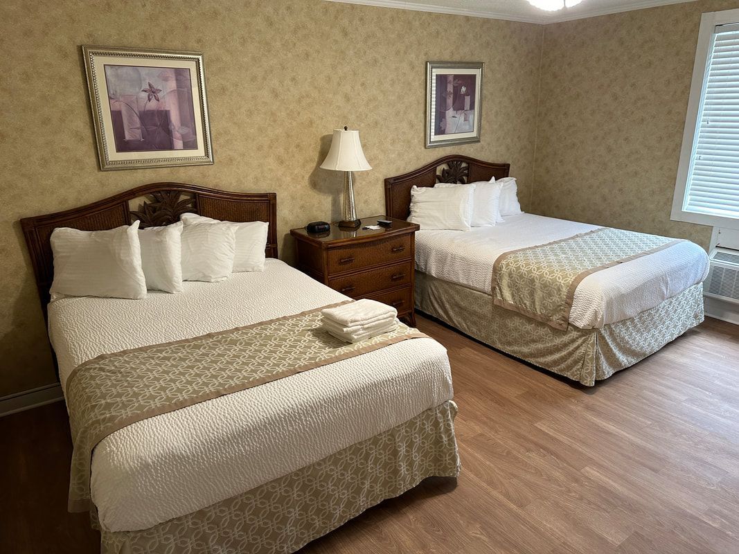 A hotel room with two beds , a nightstand and a window.