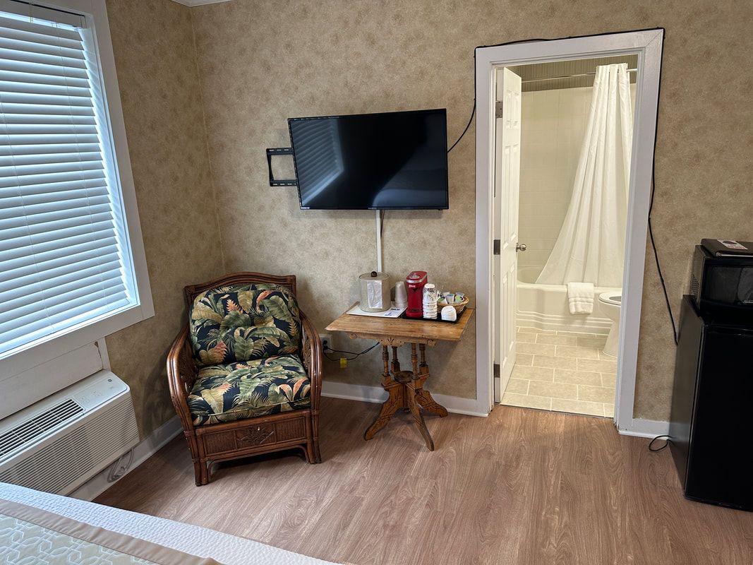 A hotel room with a chair , table and television.