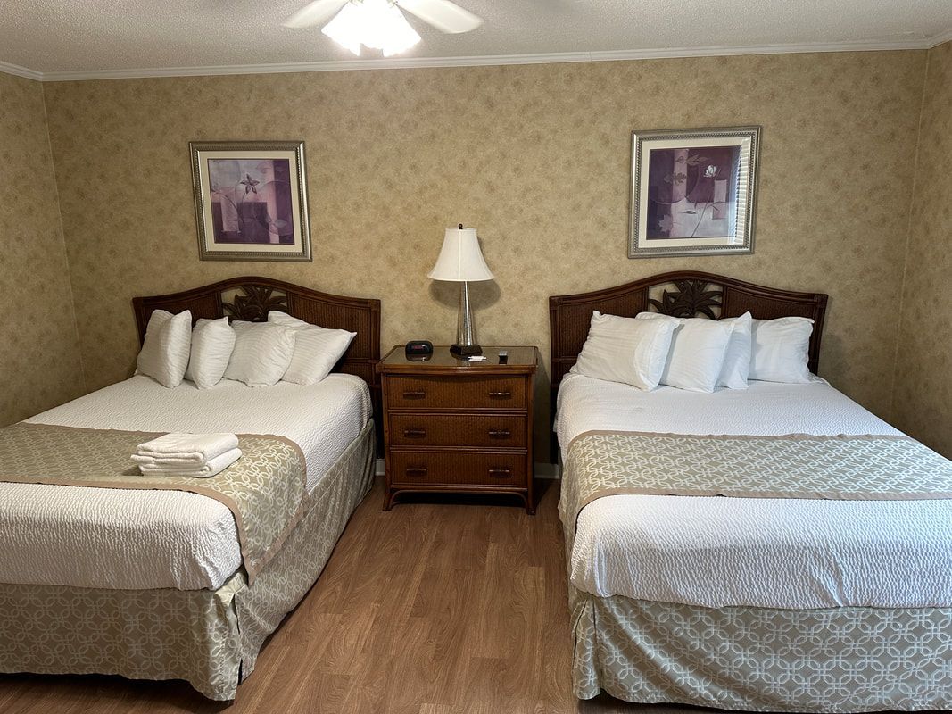 A hotel room with two beds , a nightstand , and a ceiling fan.