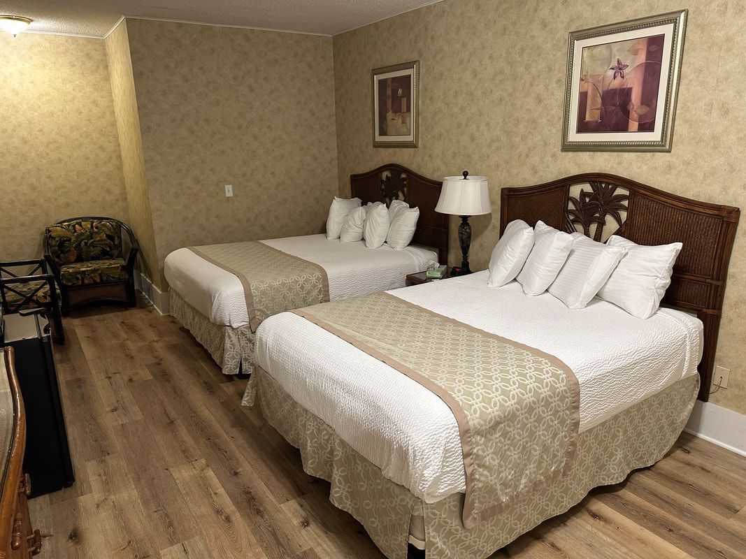 A hotel room with two beds and a chair.