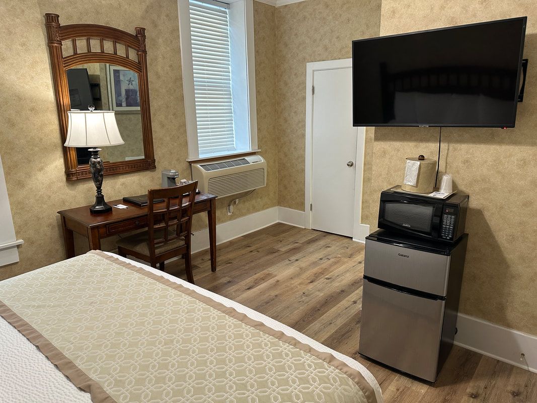 A hotel room with a bed , desk , microwave and television.
