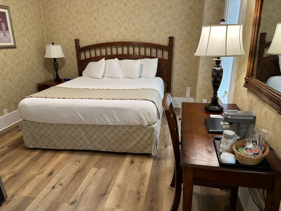 A hotel room with a bed , desk , lamp and mirror.