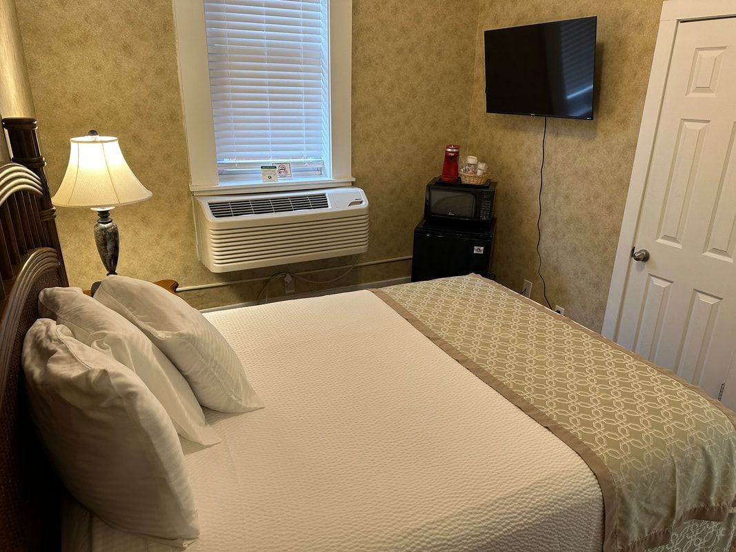 A hotel room with a bed , television , lamp and window.