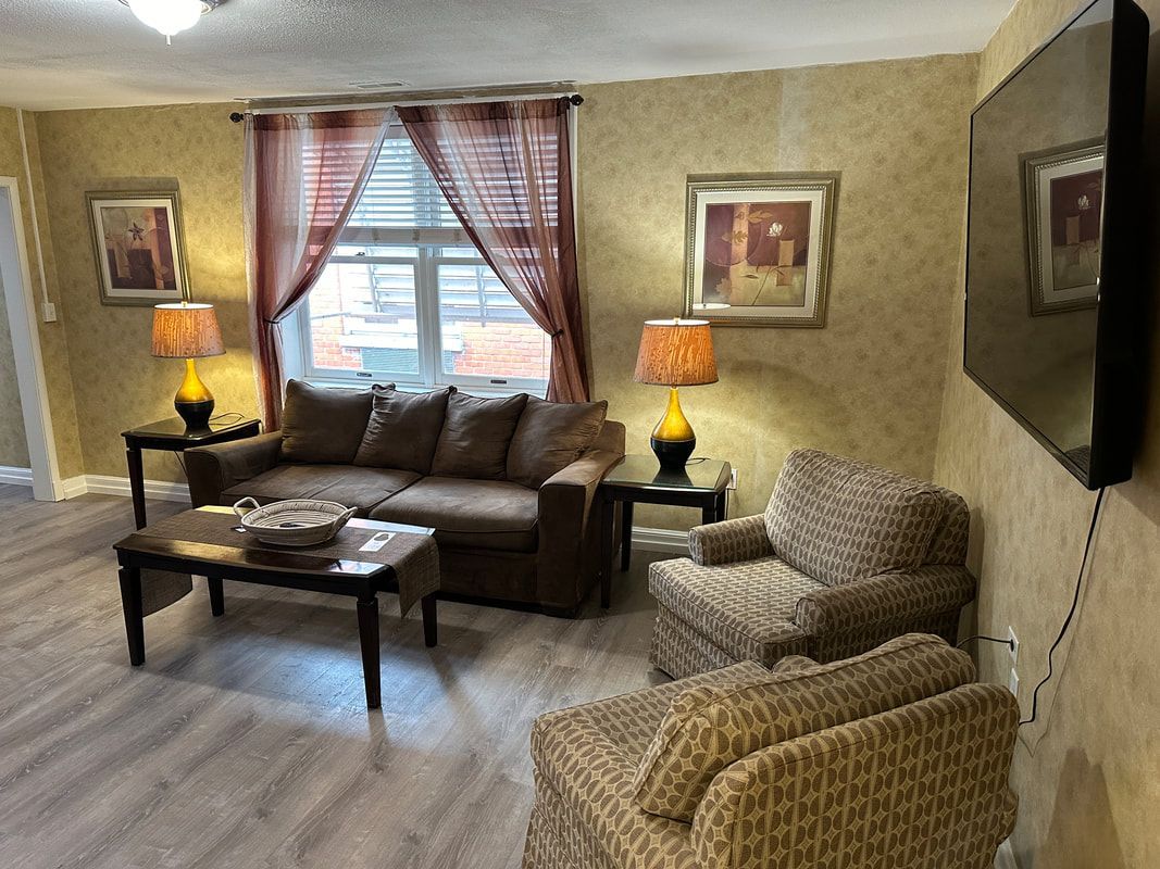 A living room with a couch , chairs , coffee table and television.