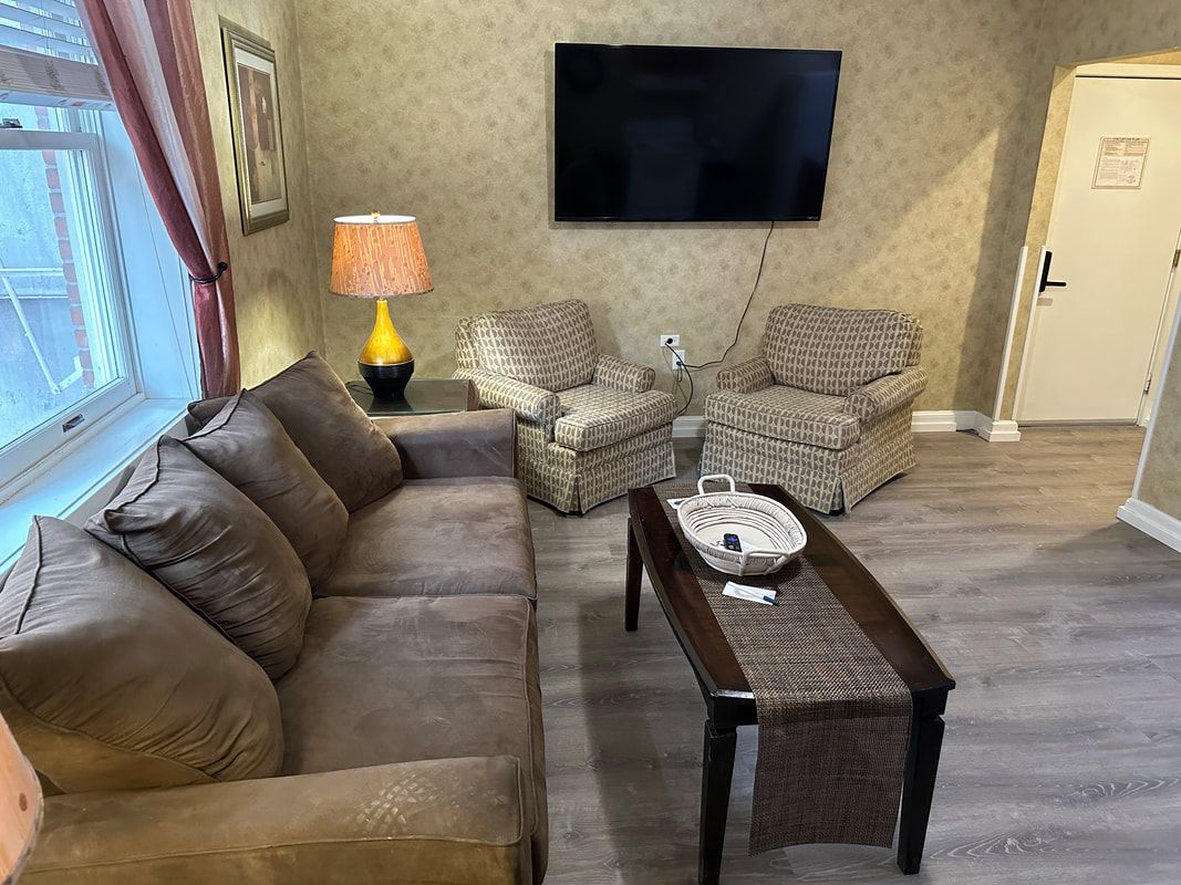A living room with a couch , chairs , coffee table and television.