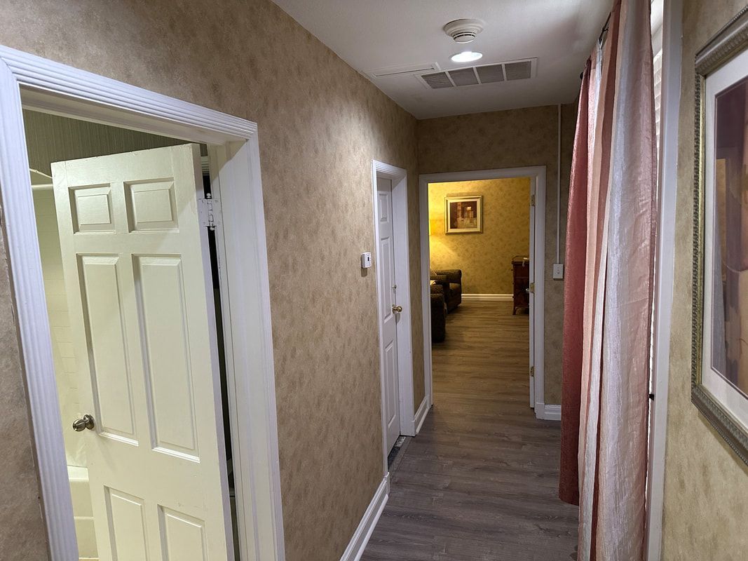 A long hallway with a door open and a picture on the wall.