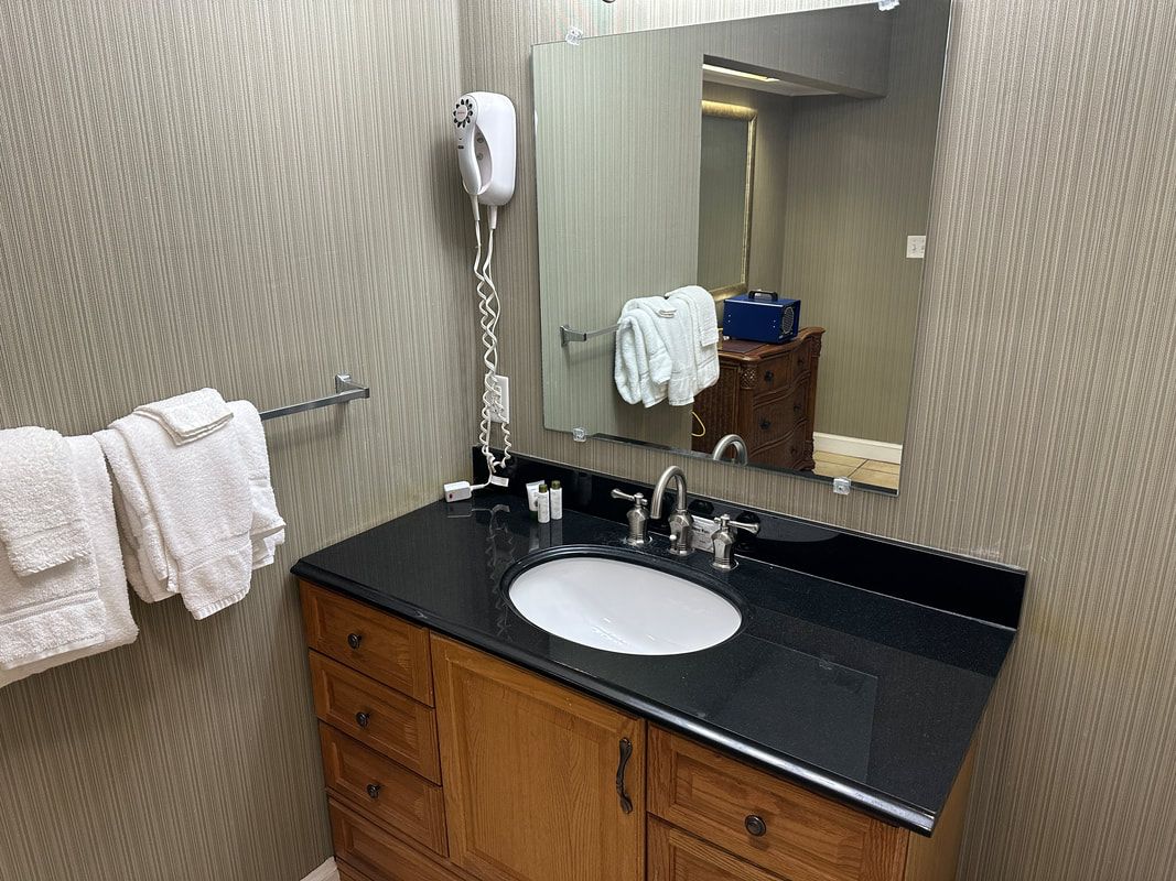A bathroom with a sink , mirror and towel rack.
