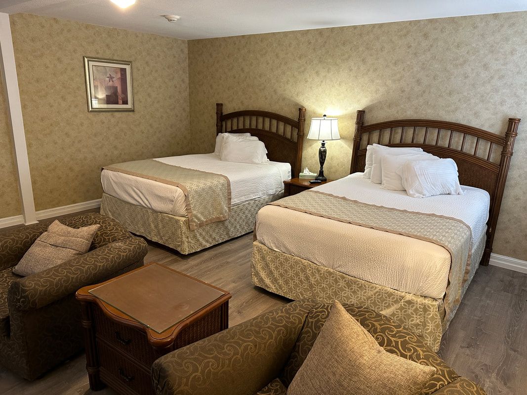 A hotel room with two beds and two chairs.