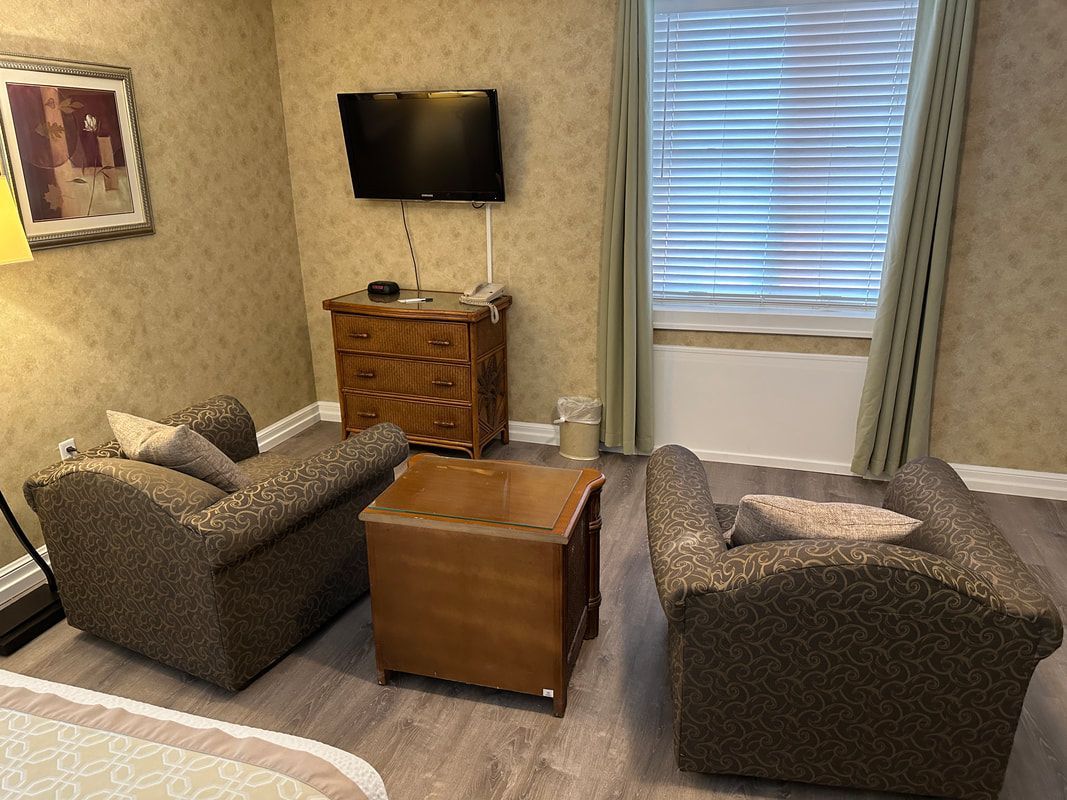 A living room with two chairs , a table and a television.