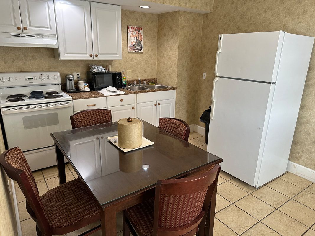 A kitchen with a table and chairs and a refrigerator.