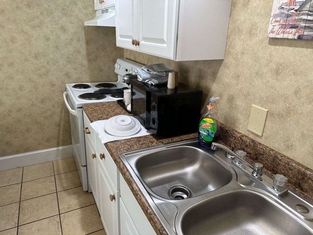 A kitchen with a sink , stove and microwave.