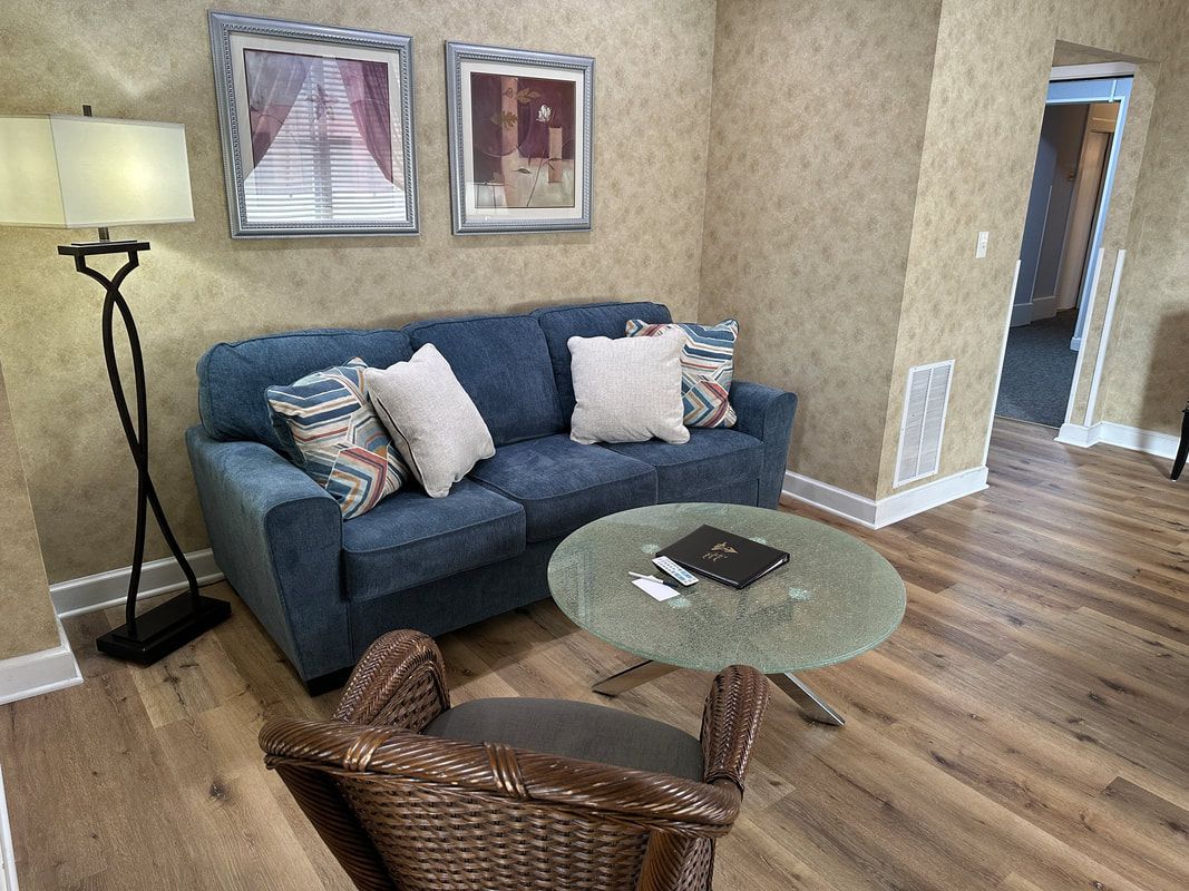 A living room with a couch , chair , table and lamp.