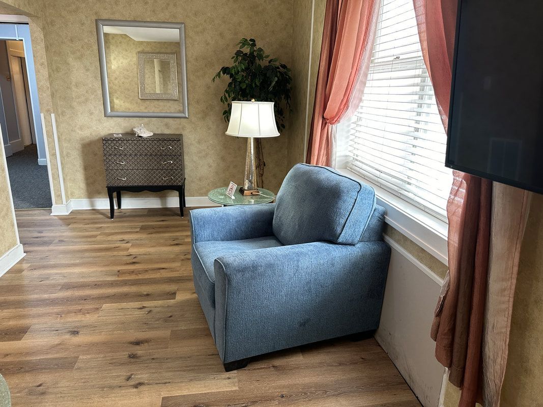 A blue chair is sitting in a living room next to a window.