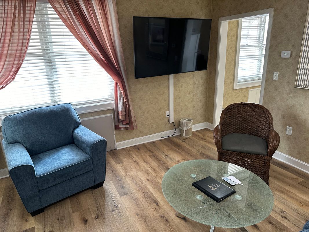 A living room with two chairs , a table , and a flat screen tv.
