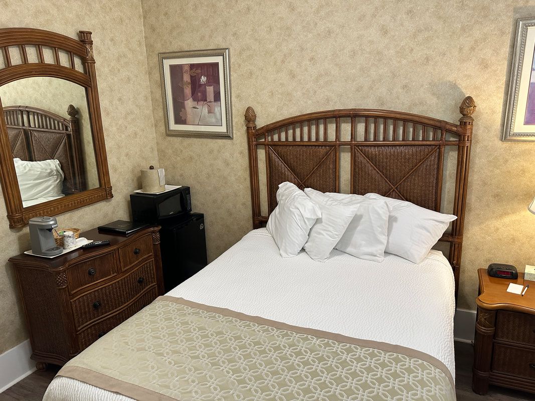 A hotel room with a bed , nightstand , mirror and microwave.