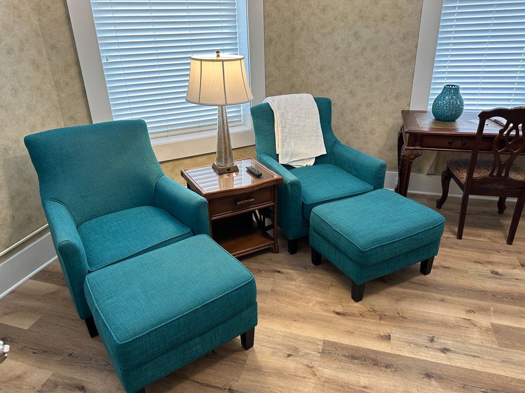 A living room with two blue chairs and two ottomans.