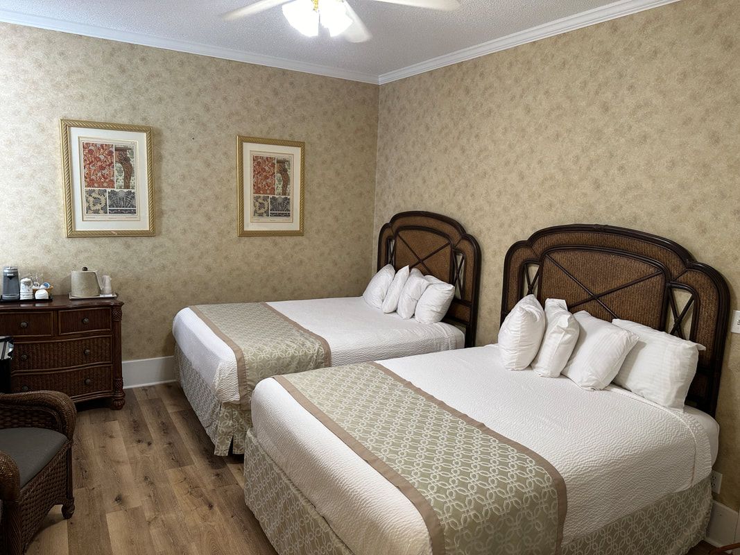 A hotel room with two beds and a ceiling fan.