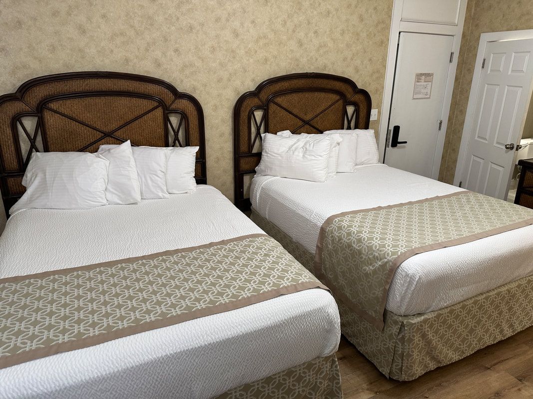 A hotel room with two beds and a door.