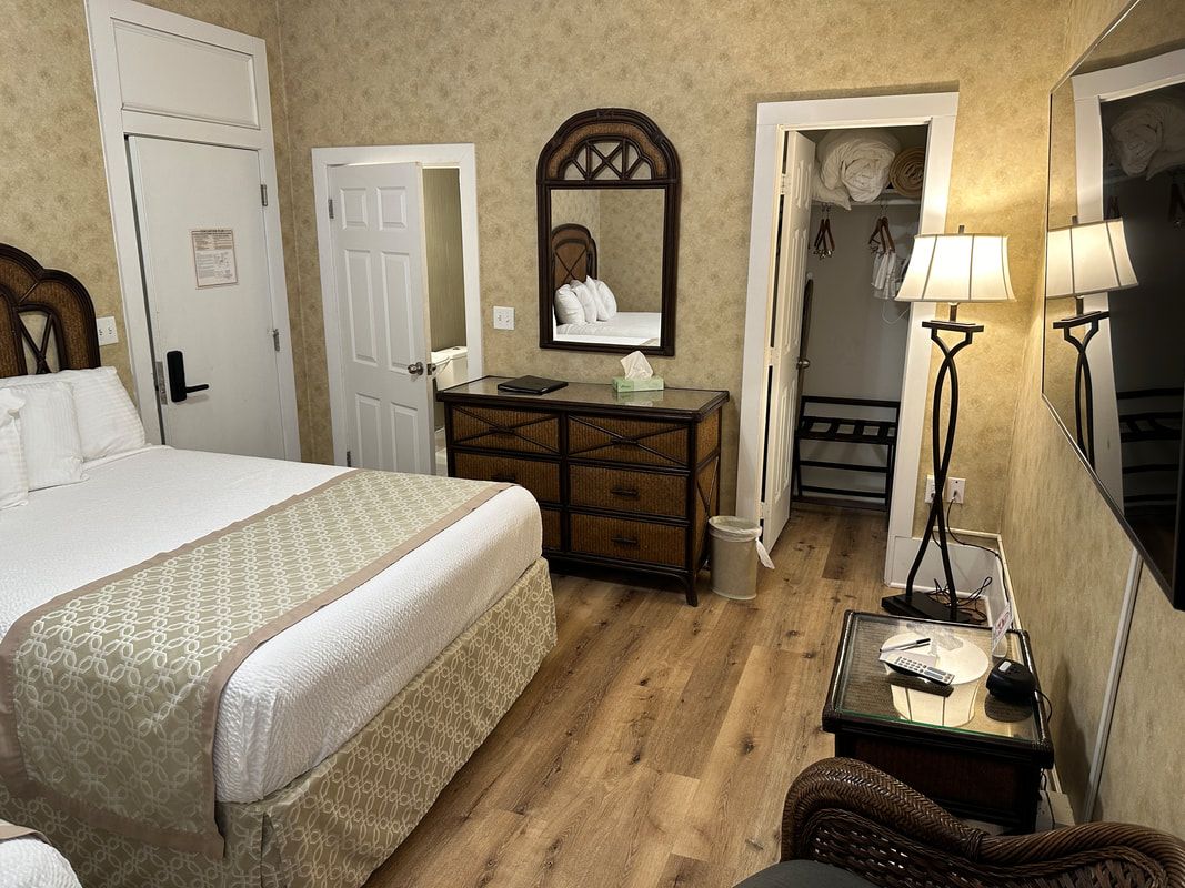 A hotel room with a bed , dresser , mirror and television.