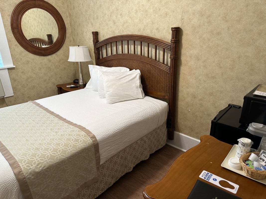 A hotel room with a bed , table and mirror.