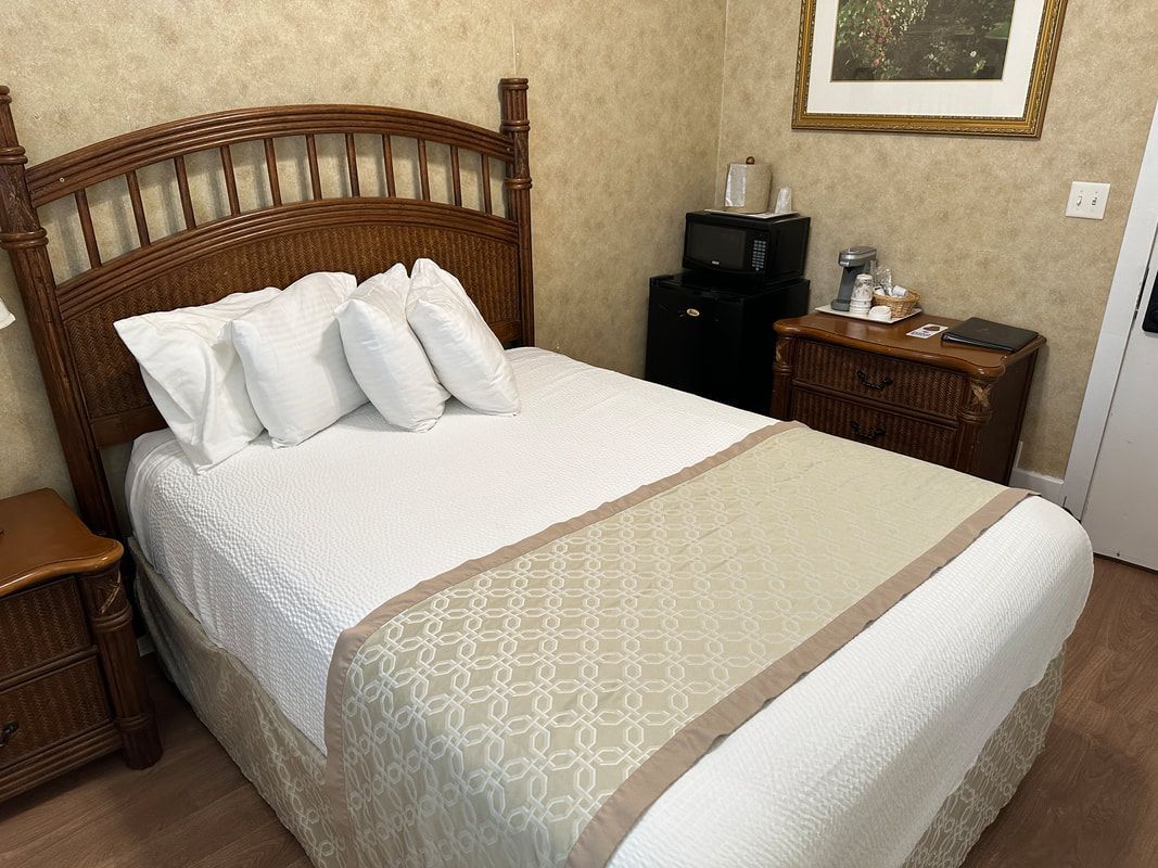 A hotel room with a bed , nightstand and microwave