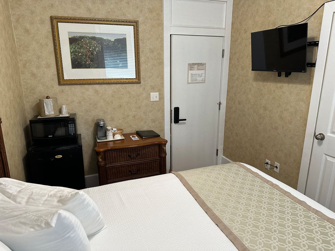 A hotel room with a bed , dresser , and television.