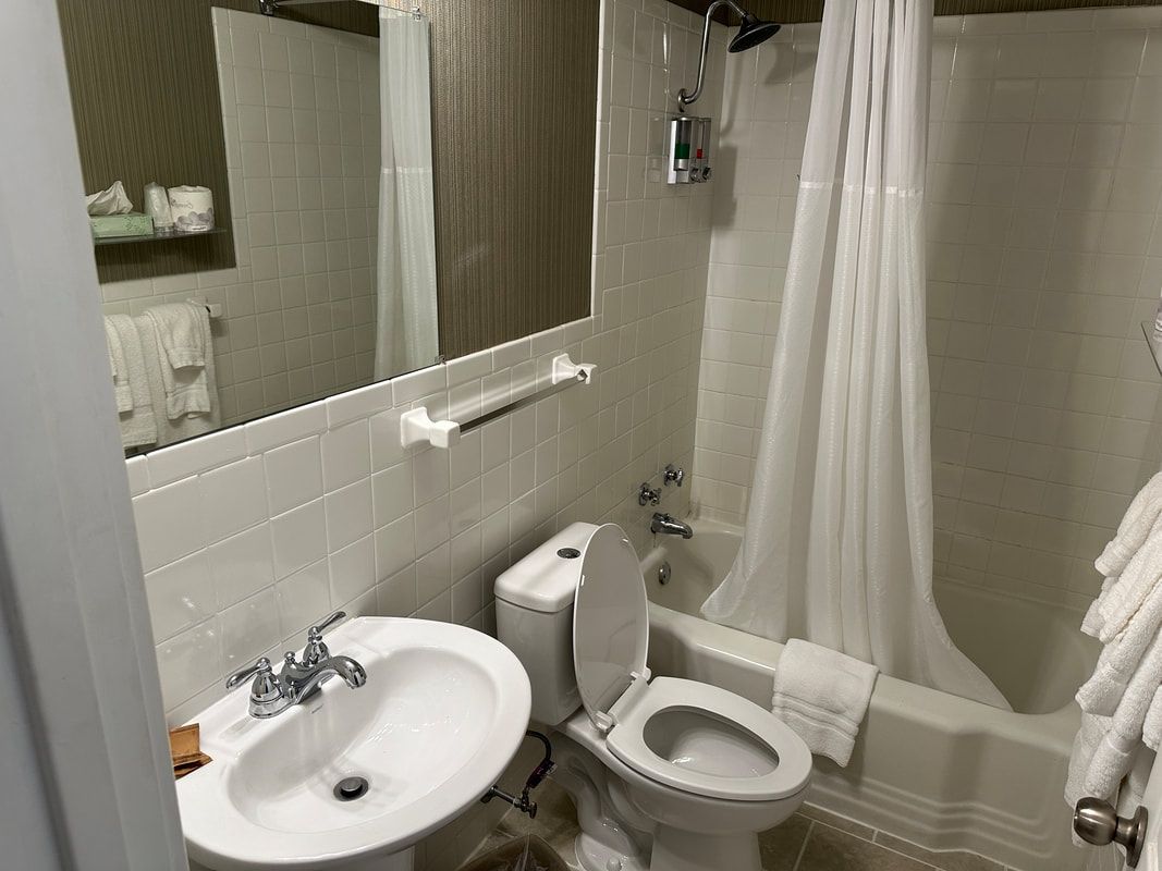 A bathroom with a sink , toilet , tub and mirror.